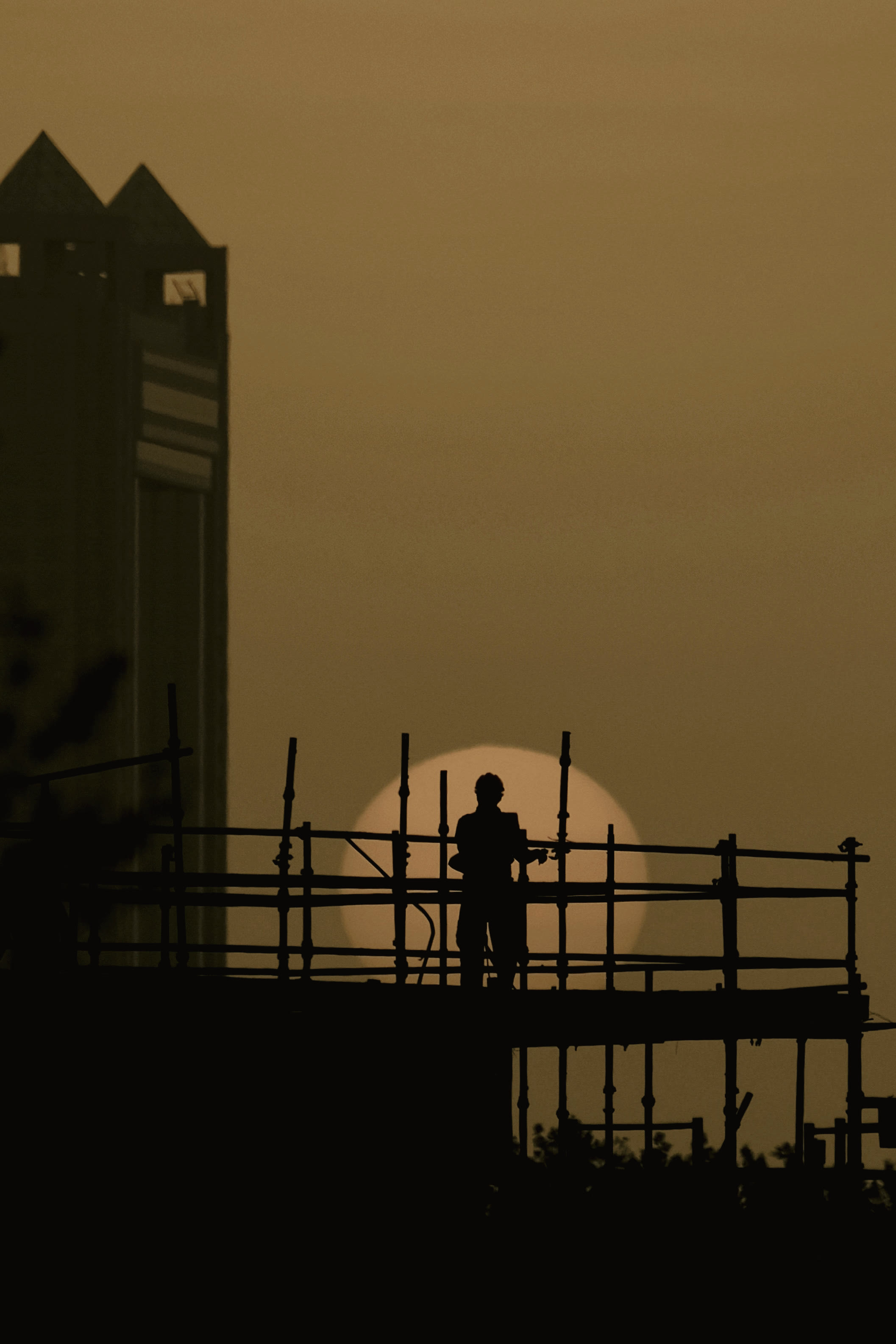 Workers silhouetted on scaffolding against an orange sunset