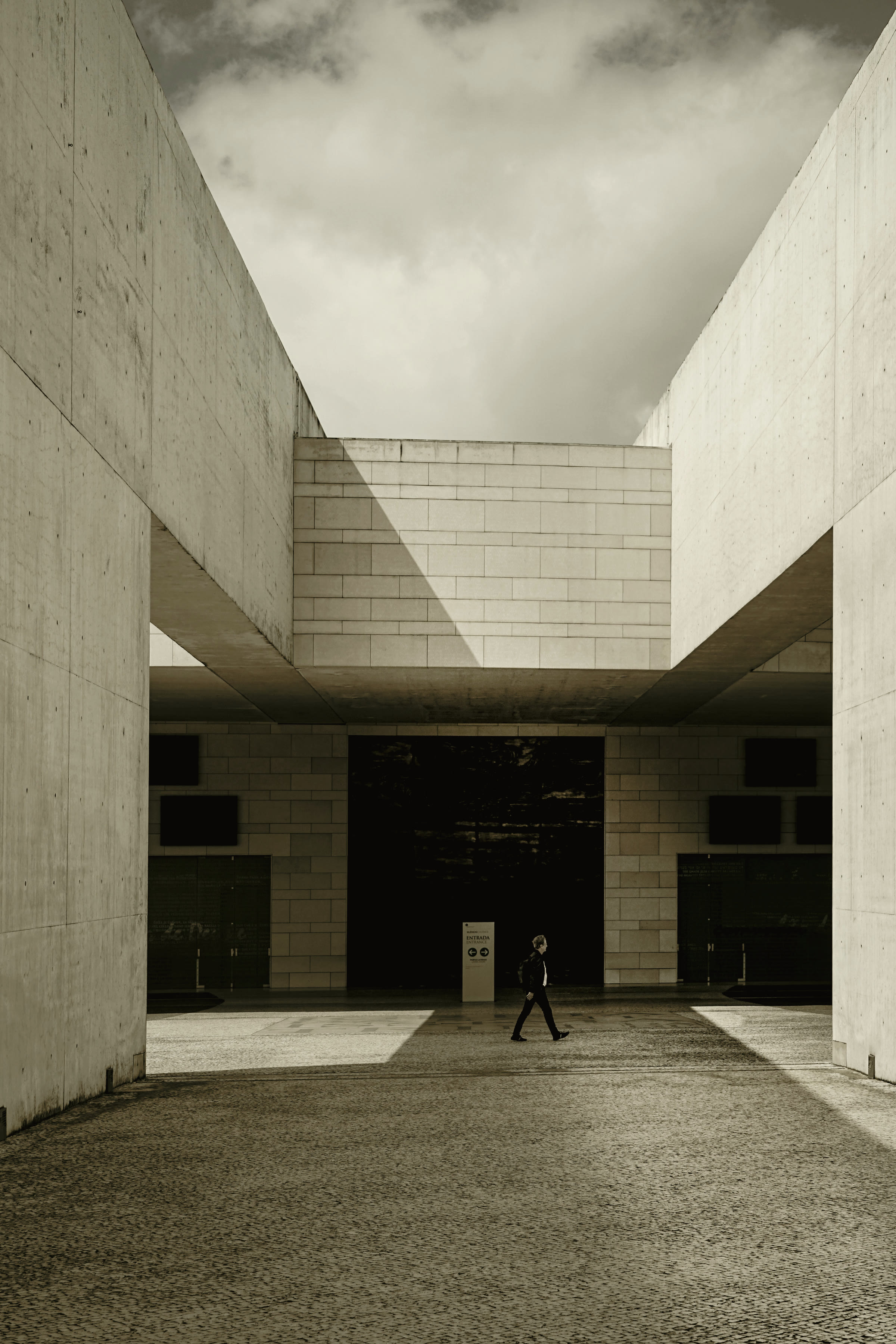 A person walking past a minimalist concrete facade